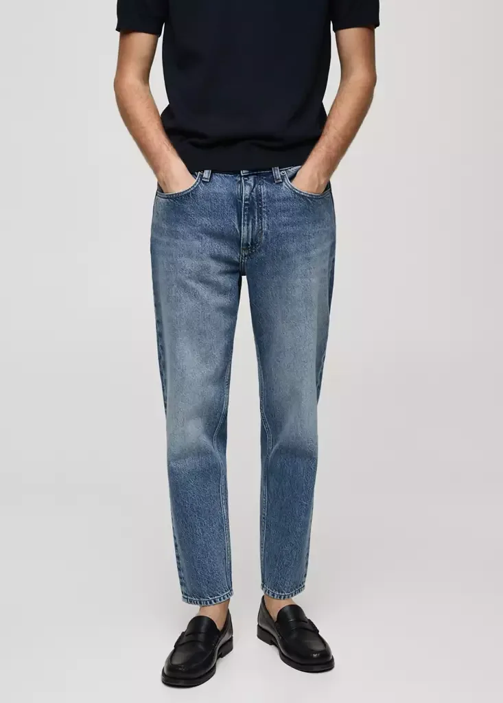 Male model wearing cropped carrot fit tapered jeans.