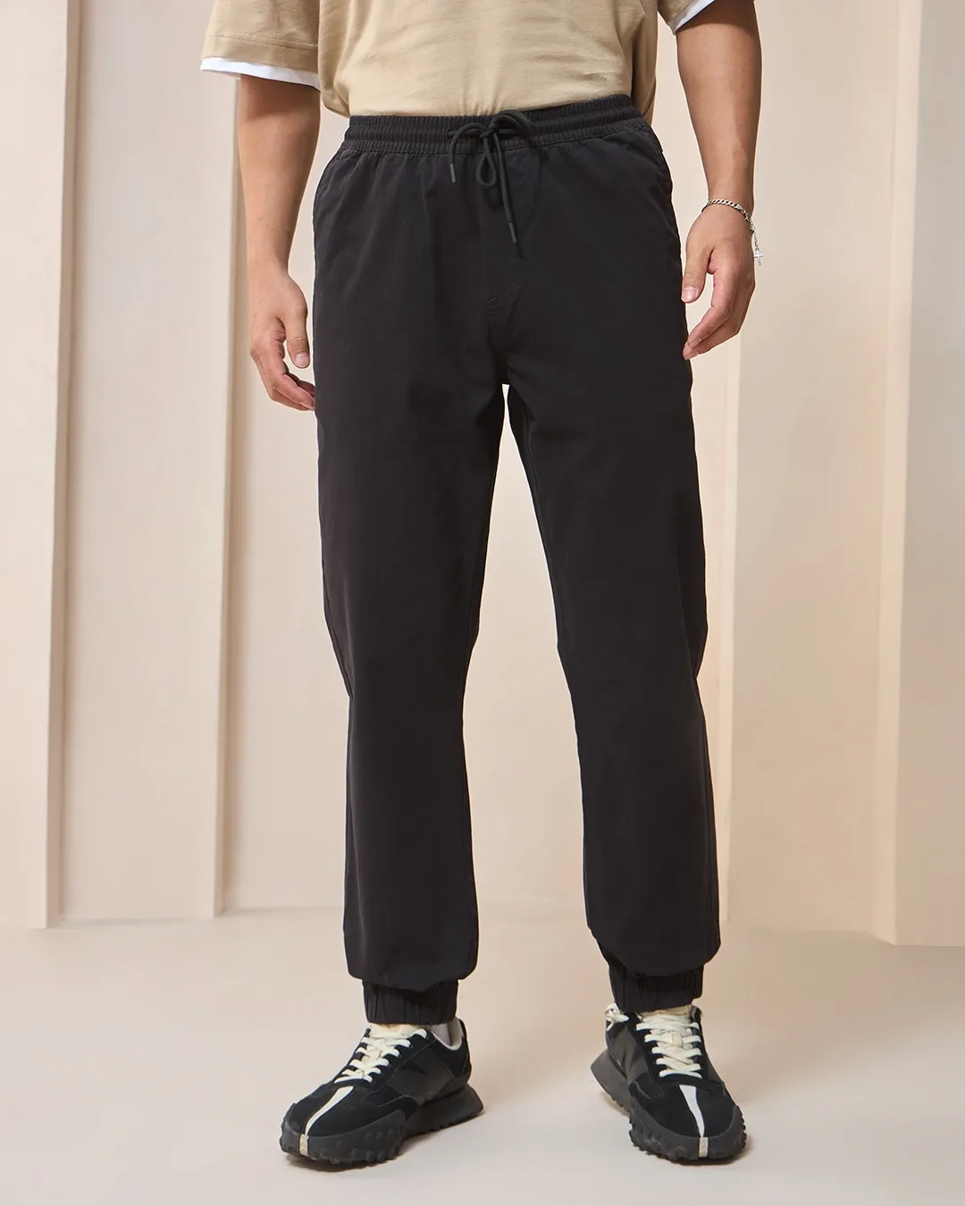 Male model wearing black jogger-style pants with an elastic cuff.