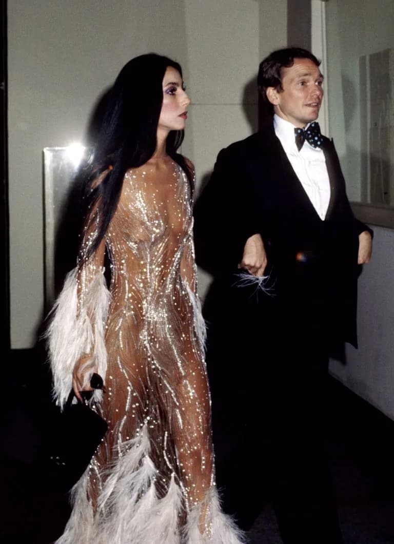 Cher in Bob Mackie wearing a sheer feathered naked dress at the 1974 Met Gala.