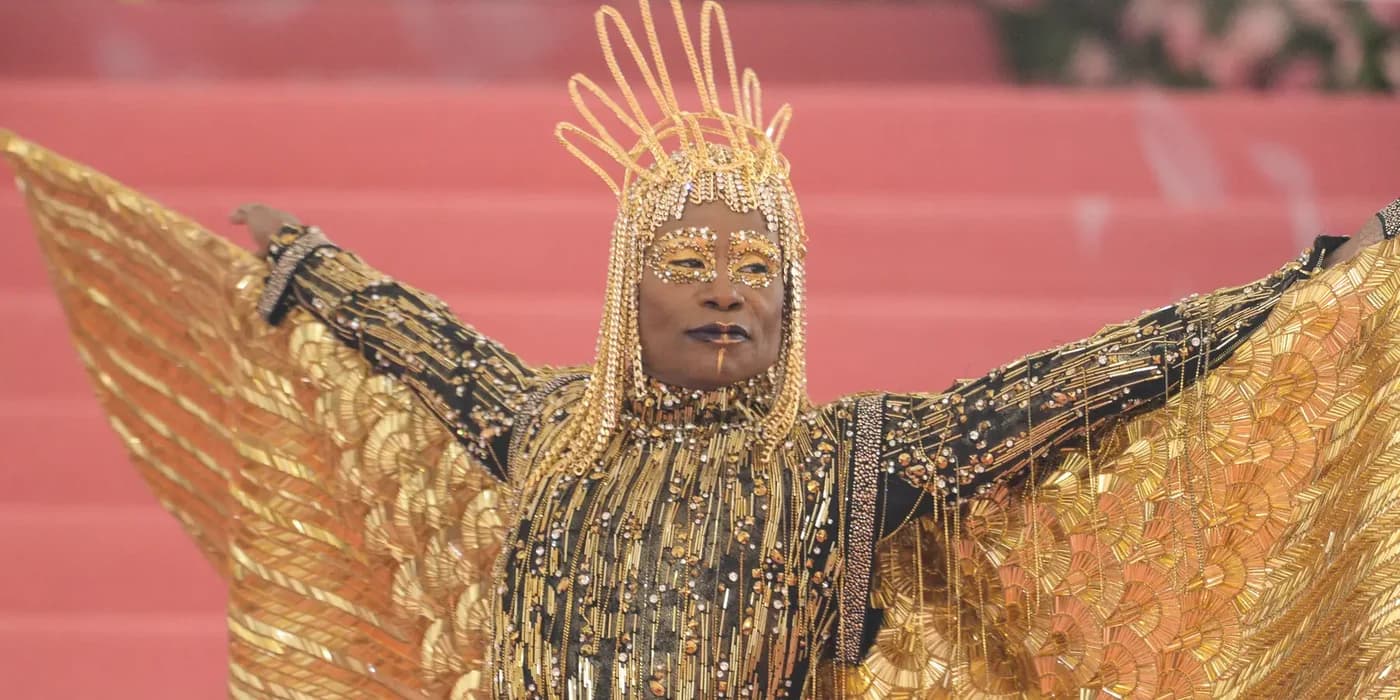 Billy Porter wearing a gold Sun God look with winged cape at the 2019 Met Gala.