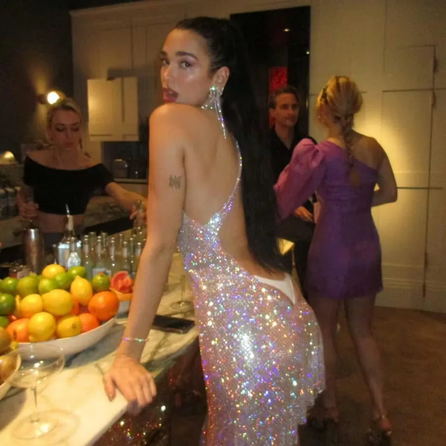 Dua Lipa wearing a sparkling backless dress with visible thong styling at a New Year event.