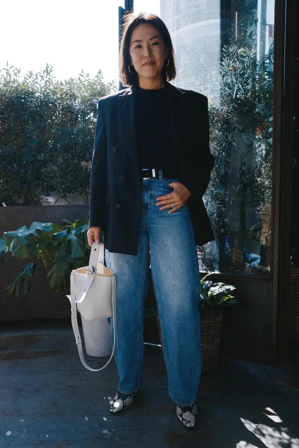 Woman wearing sculptural barrel-leg jeans with a curved outside leg line.