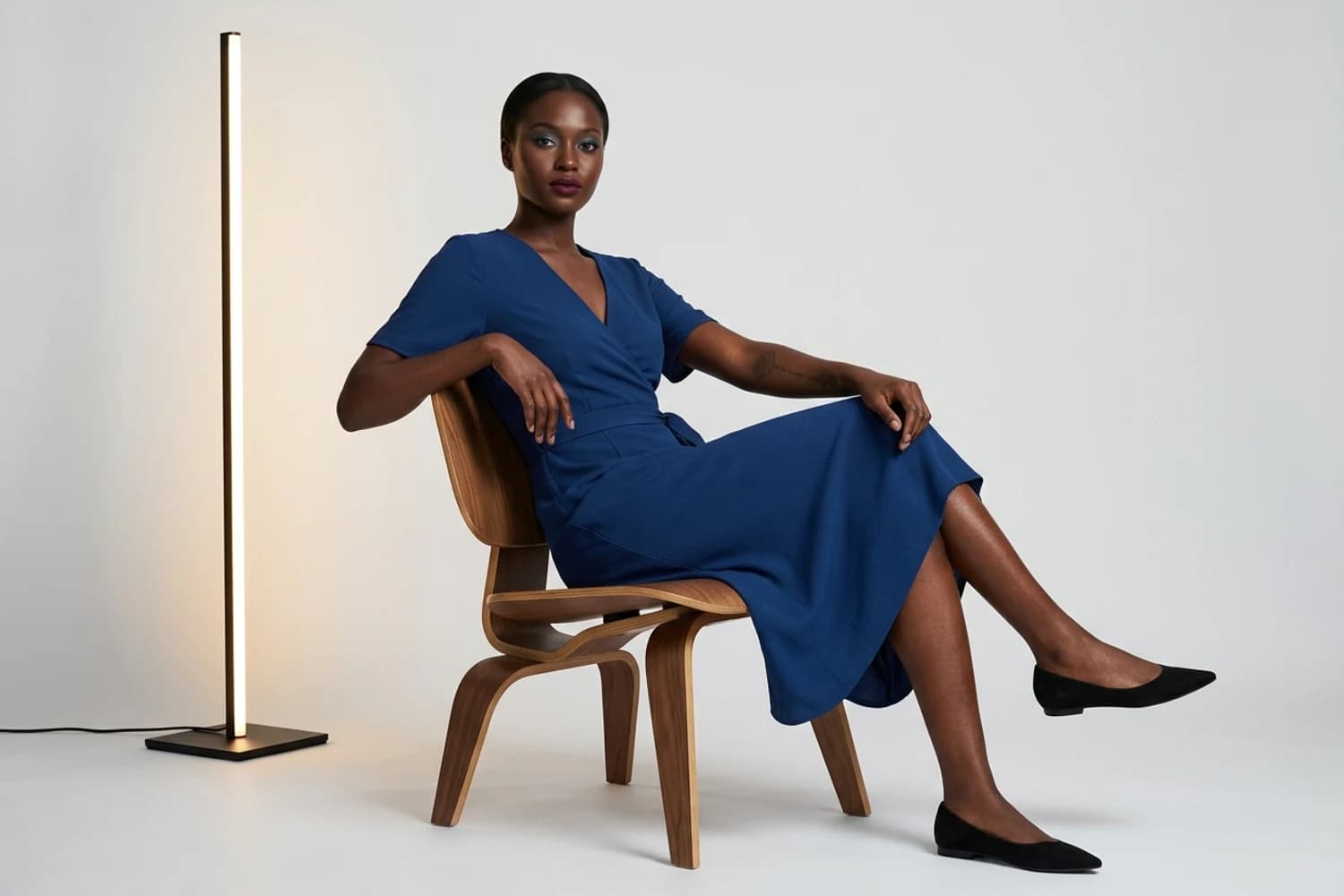 Sophisticated studio portrait of a woman seated beside a vertical floor lamp